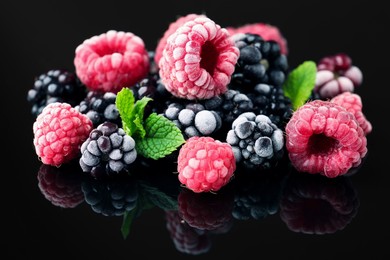 Photo of Many different frozen berries and mint on black table, closeup