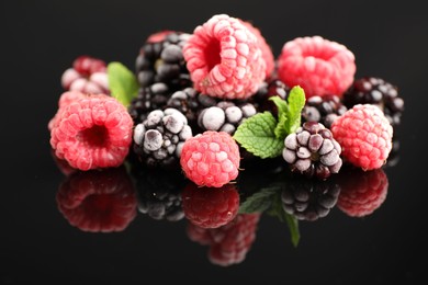 Photo of Many different frozen berries and mint on black table, closeup