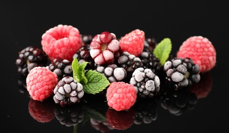 Photo of Many different frozen berries and mint on black table, closeup