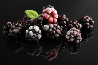 Photo of Frozen blackberries and mint on black table, closeup