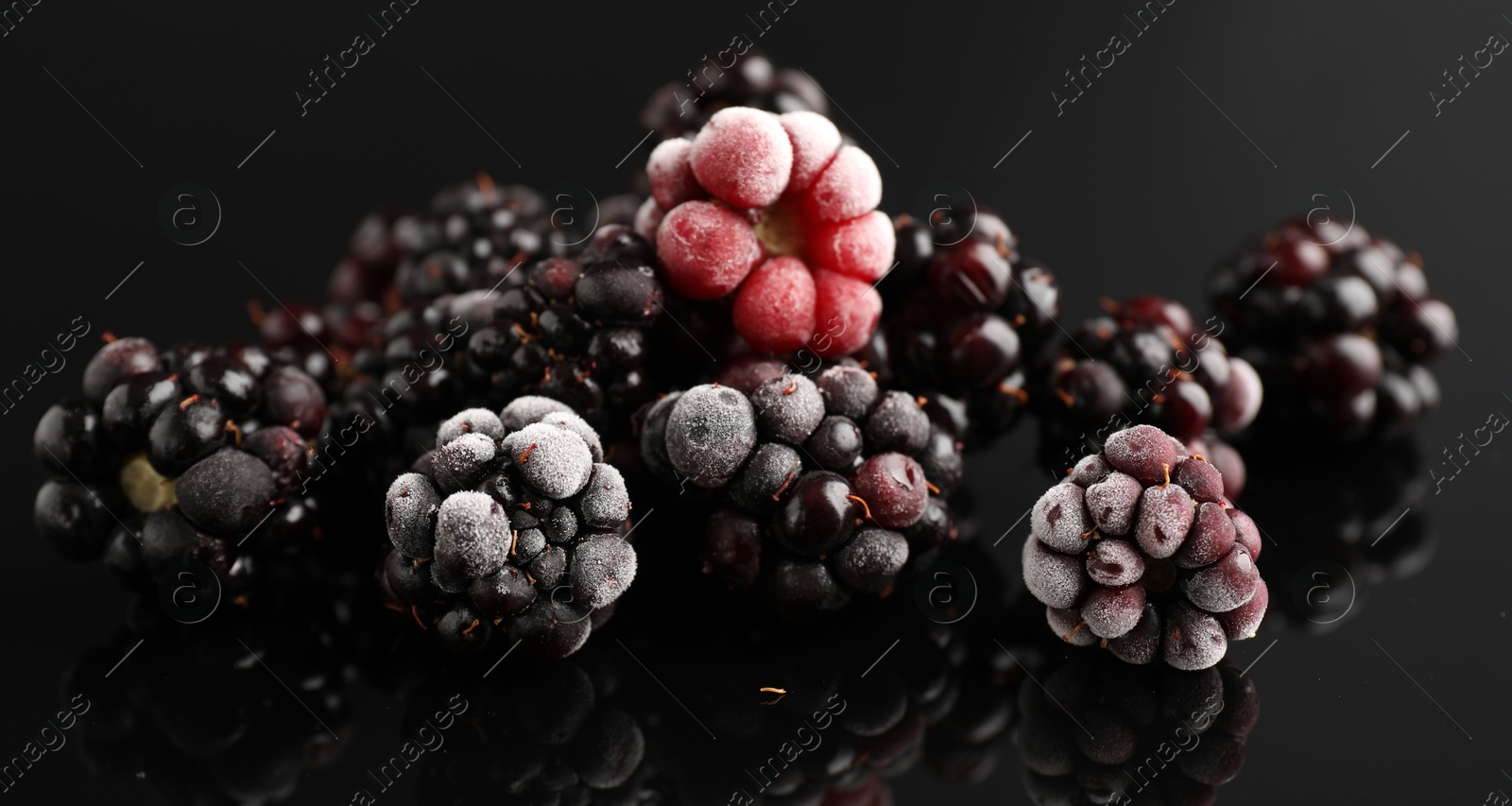 Photo of Many frozen blackberries on black table, closeup