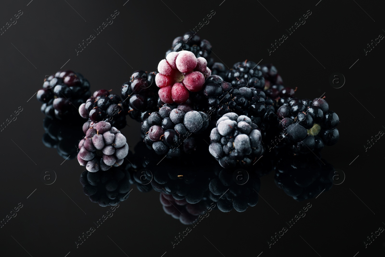 Photo of Many ripe frozen blackberries on black table