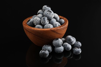 Photo of Many frozen blueberries in bowl on black table, closeup