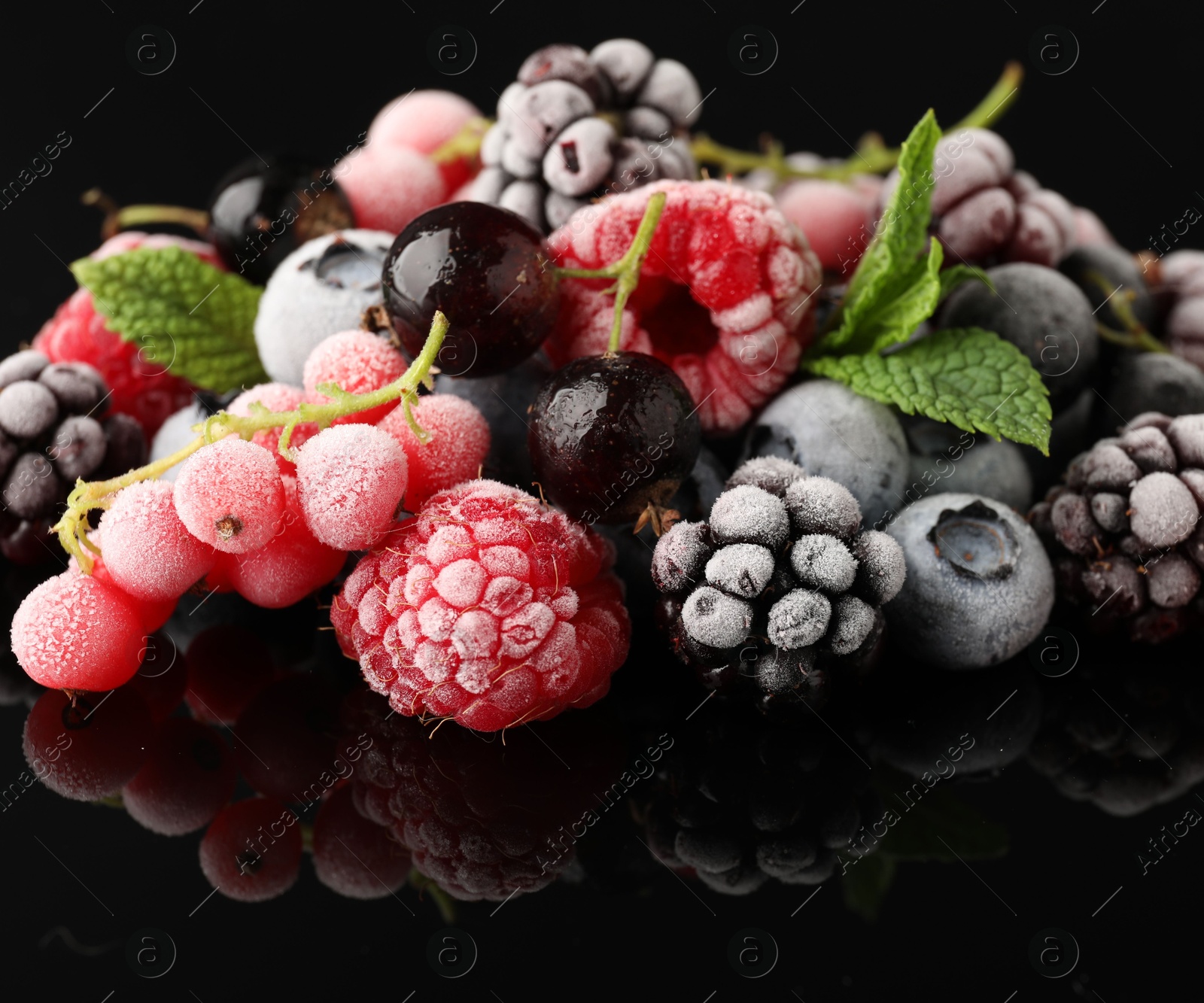 Photo of Many different frozen berries and mint on black table, closeup
