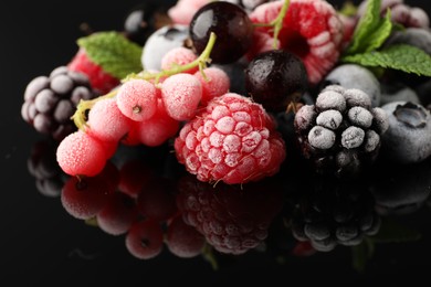 Photo of Many different frozen berries and mint on black table, closeup