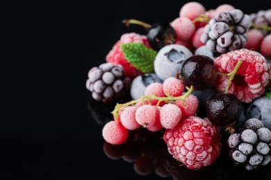 Photo of Many different frozen berries on black table, closeup. Space for text