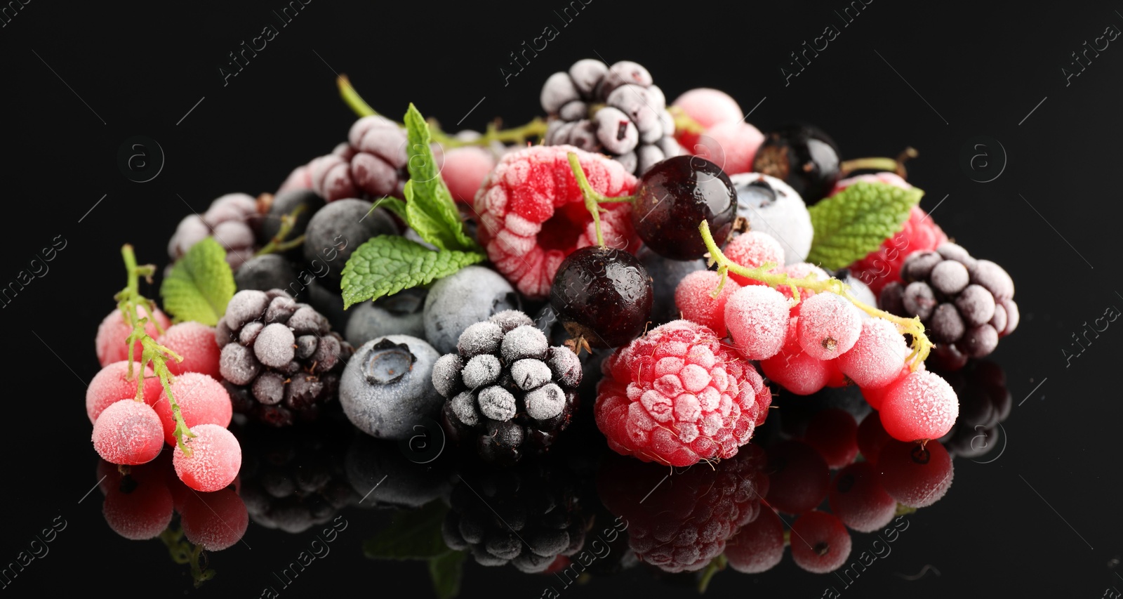 Photo of Many different frozen berries and mint on black table, closeup