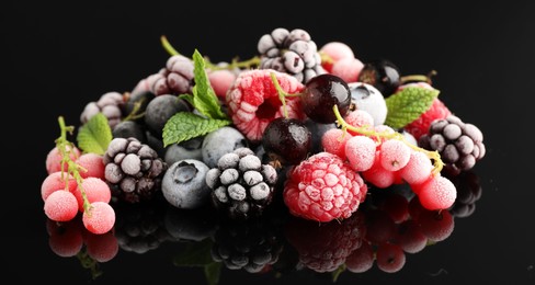 Photo of Many different frozen berries and mint on black table, closeup