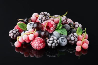 Photo of Many different frozen berries and mint on black table, closeup