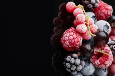 Photo of Many different frozen berries on black table, closeup. Space for text
