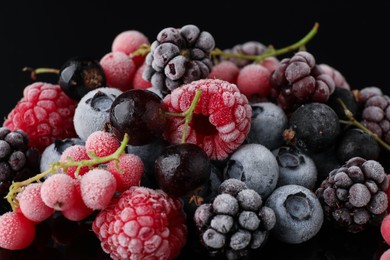 Photo of Many different frozen berries on black table, closeup
