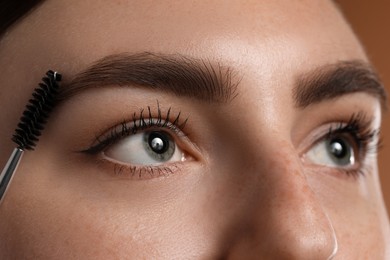 Photo of Young woman brushing her eyebrow with spoolie, closeup