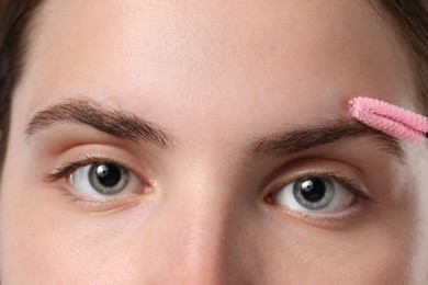 Photo of Young woman brushing her eyebrow with spoolie, closeup