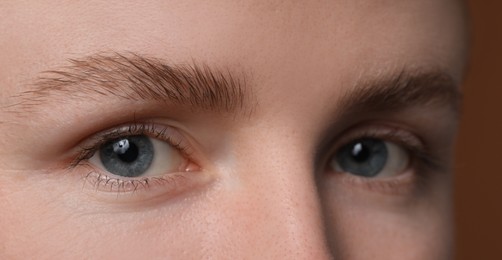 Photo of Young woman with beautiful eyebrows on brown background, closeup