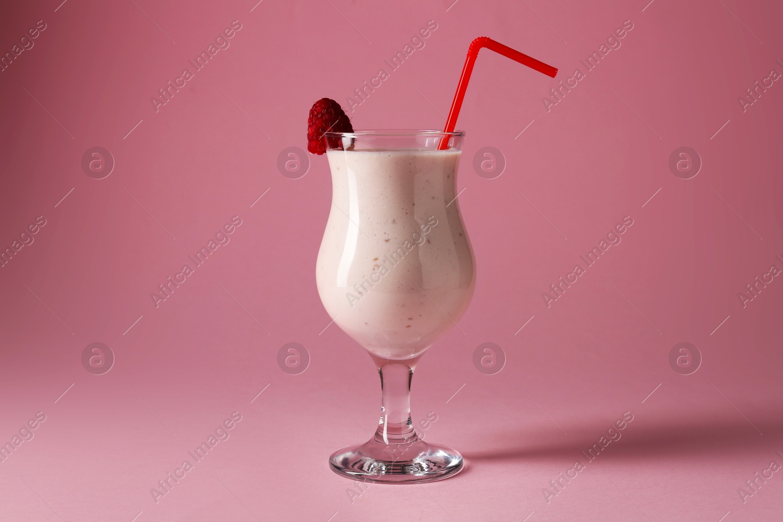 Photo of Tasty raspberry milkshake in glass on pink background