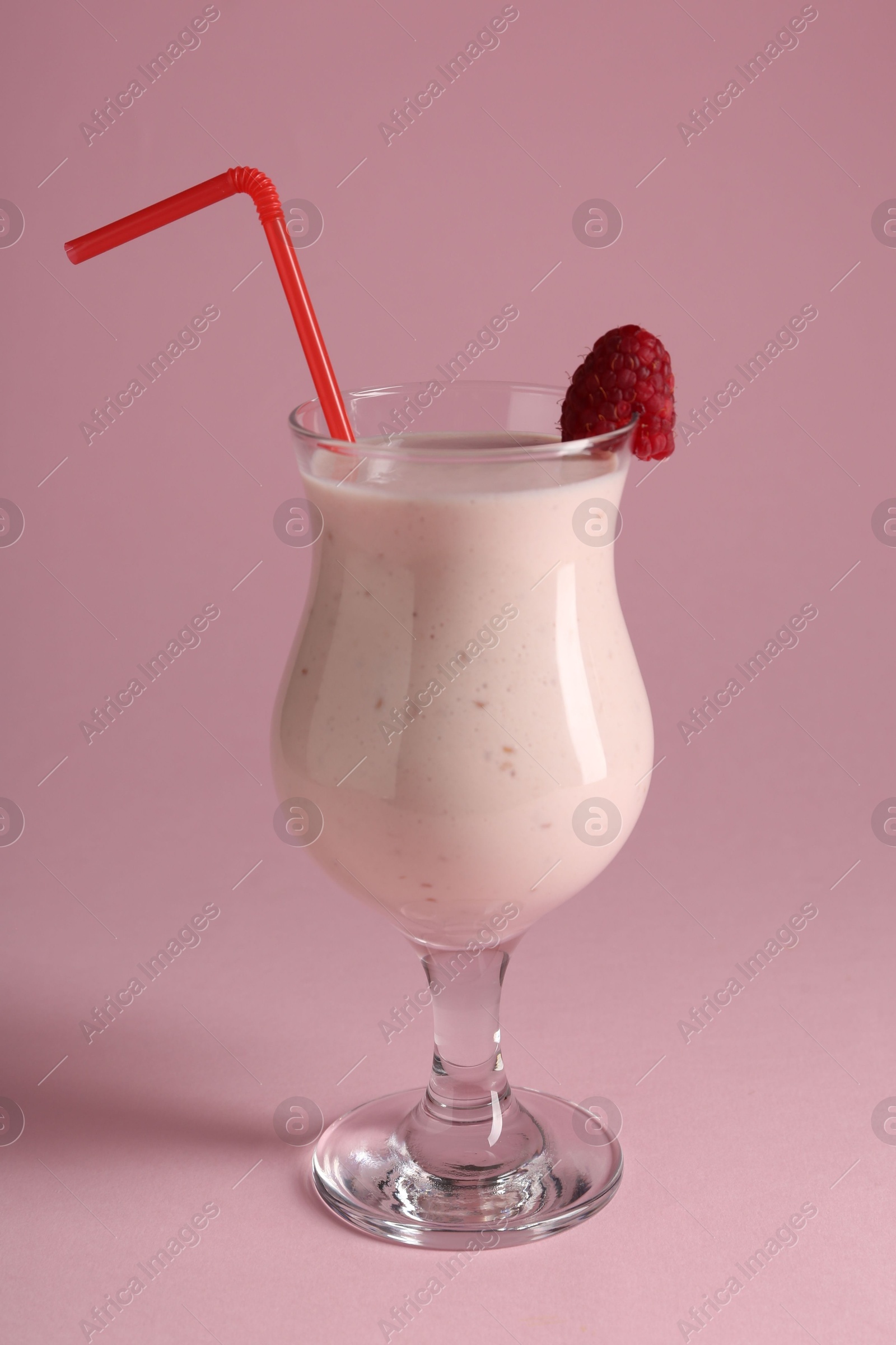 Photo of Tasty raspberry milkshake in glass on pink background