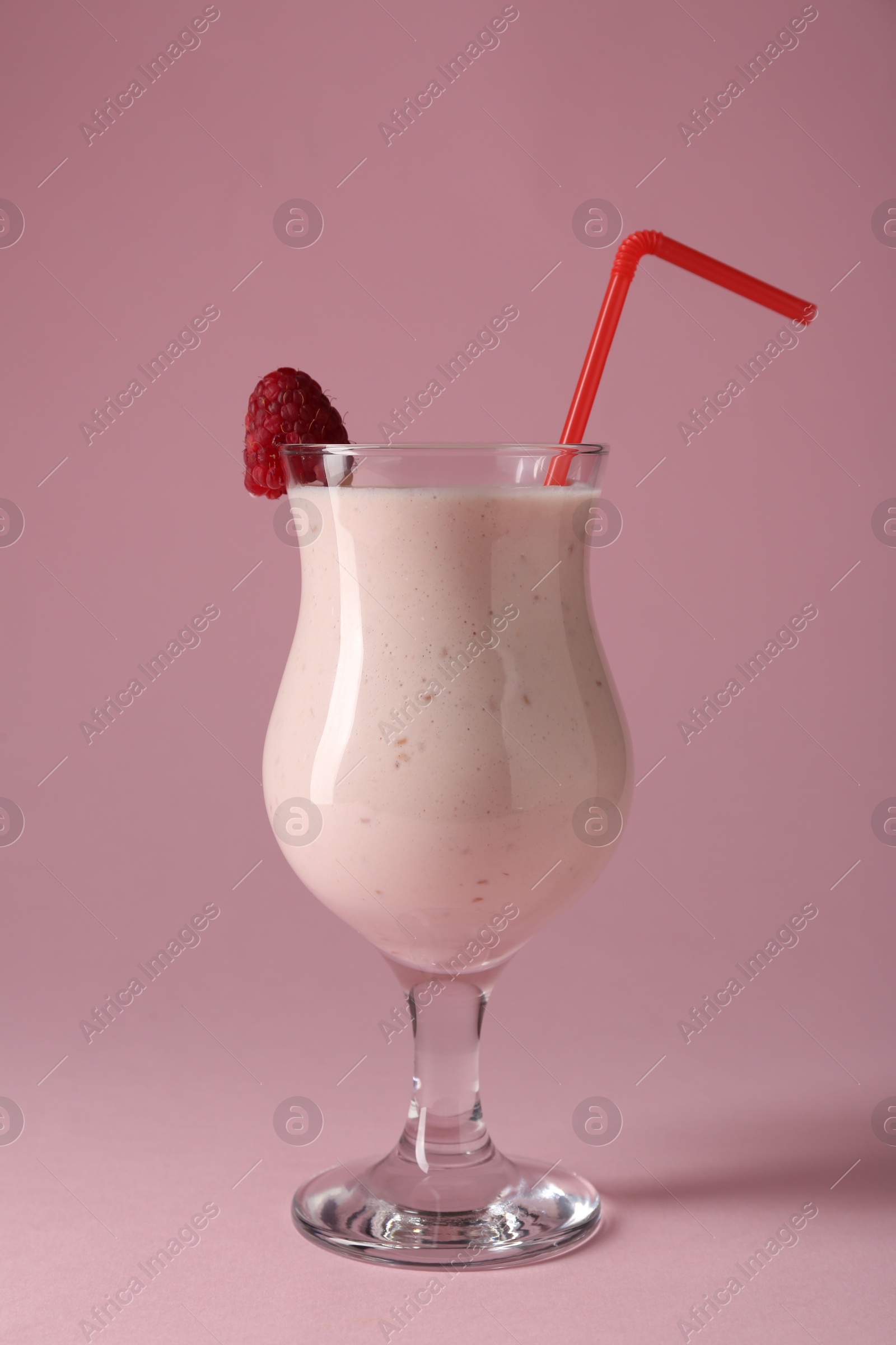 Photo of Tasty raspberry milkshake in glass on pink background