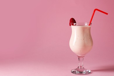 Photo of Tasty raspberry milkshake in glass on pink background, space for text