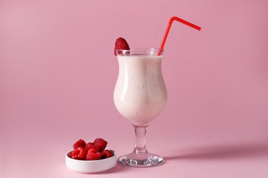 Photo of Tasty raspberry milkshake in glass and berries on pink background