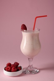 Photo of Tasty raspberry milkshake in glass and berries on pink background