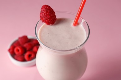 Photo of Tasty raspberry milkshake in glass and berries on pink background, closeup