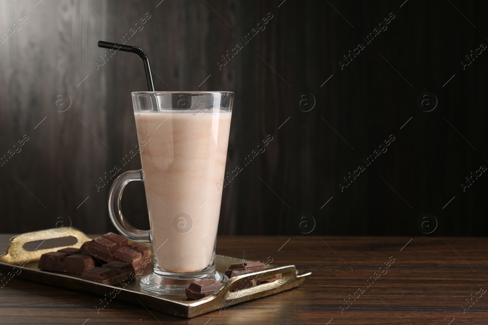 Tasty milkshake in glass and pieces of chocolate on wooden table, space for text Photo of Tasty milkshake in glass and pieces of chocolate on wooden table, space for text