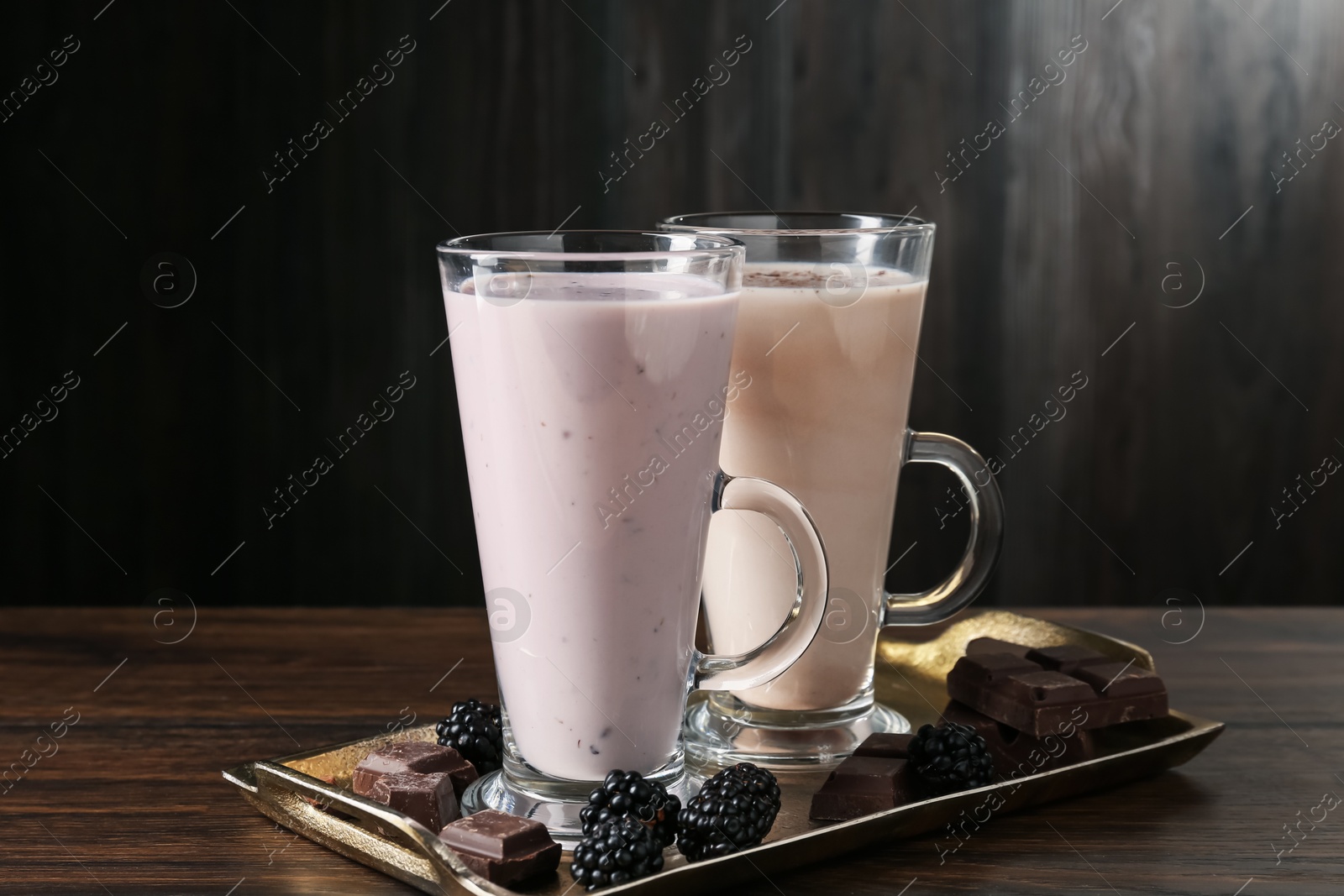 Photo of Different tasty milkshakes in glasses and ingredients on wooden table, closeup
