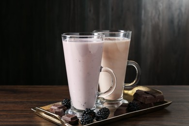 Photo of Different tasty milkshakes in glasses and ingredients on wooden table, closeup