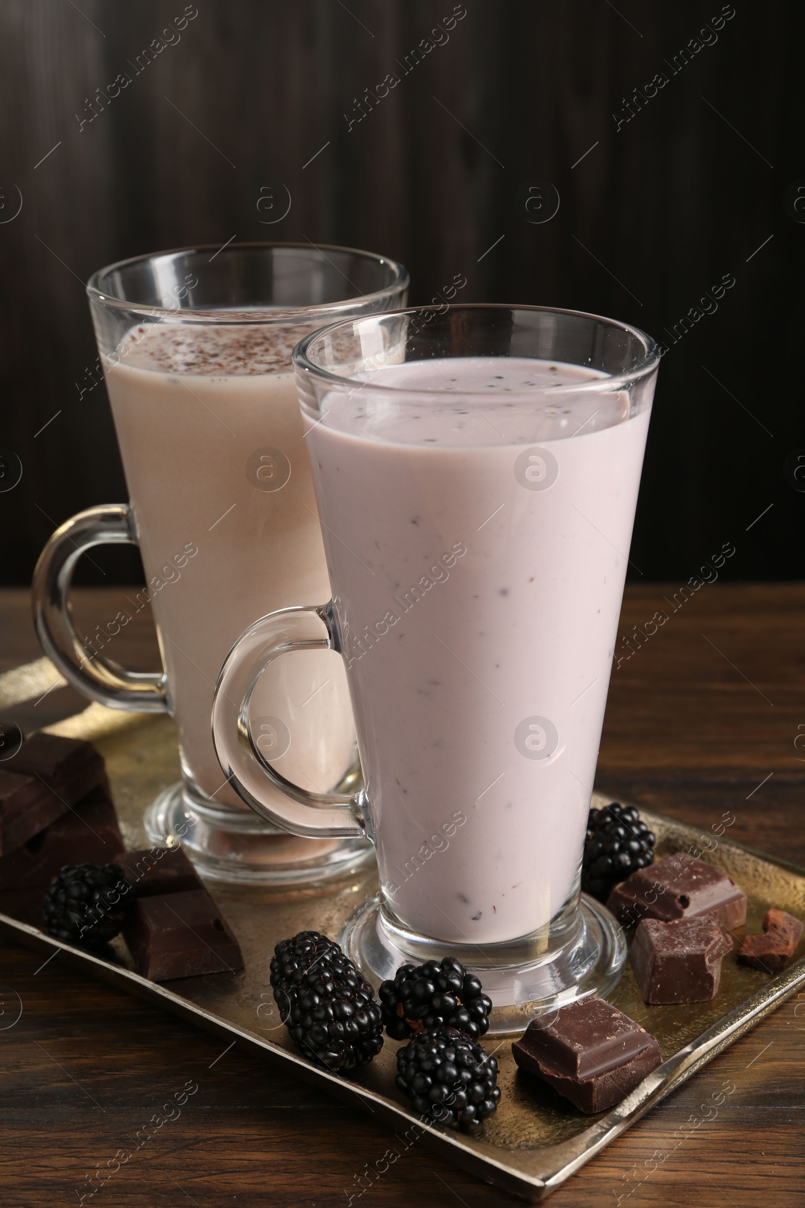Photo of Different tasty milkshakes in glasses and ingredients on wooden table, closeup