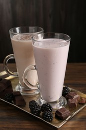 Photo of Different tasty milkshakes in glasses and ingredients on wooden table, closeup
