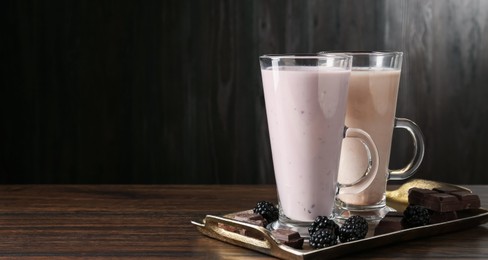 Photo of Different tasty milkshakes in glasses and ingredients on wooden table, space for text