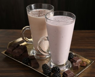 Photo of Different tasty milkshakes in glasses and ingredients on wooden table, closeup