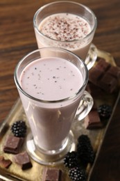 Photo of Different tasty milkshakes in glasses and ingredients on wooden table, closeup