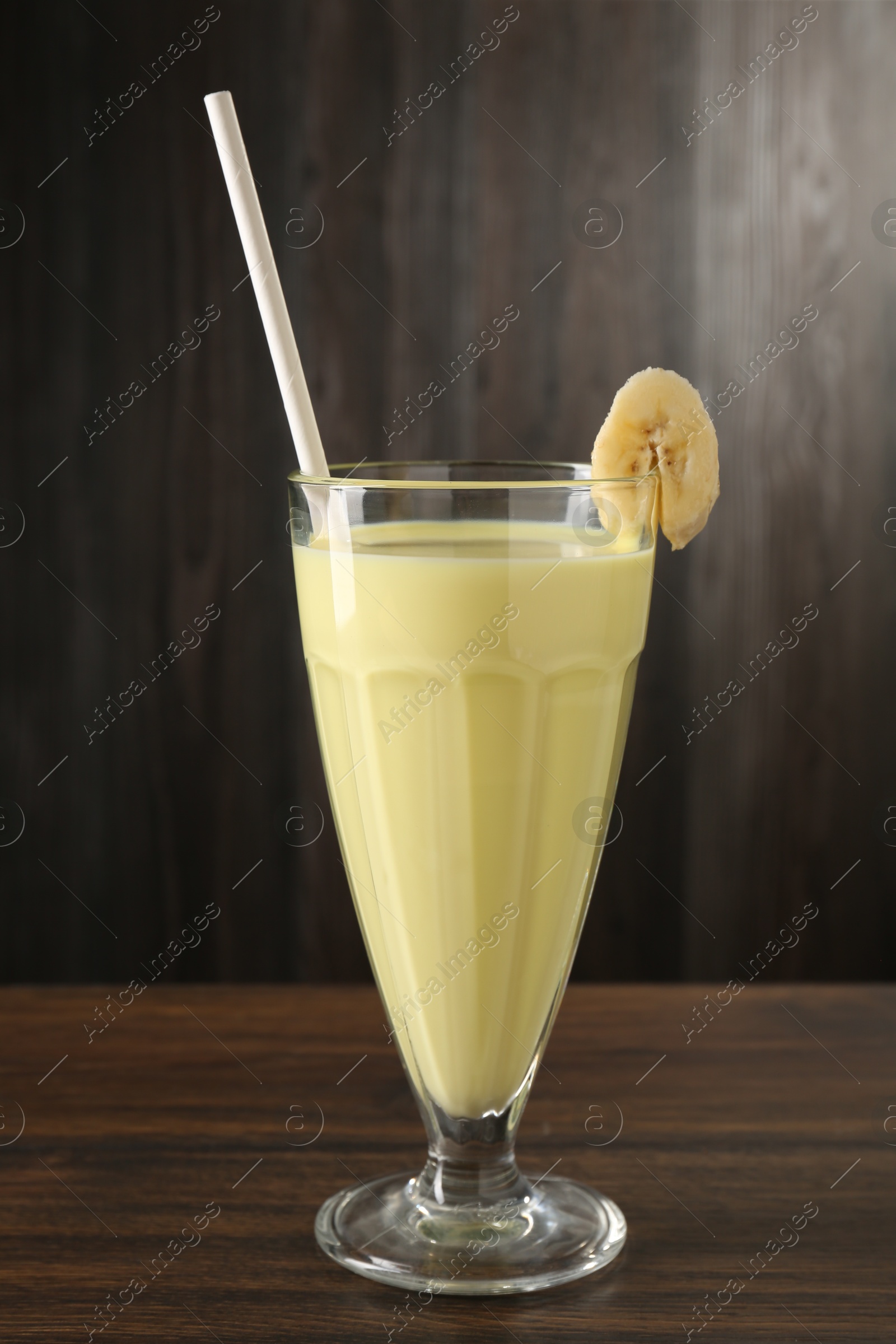 Photo of Tasty banana milkshake in glass on wooden table