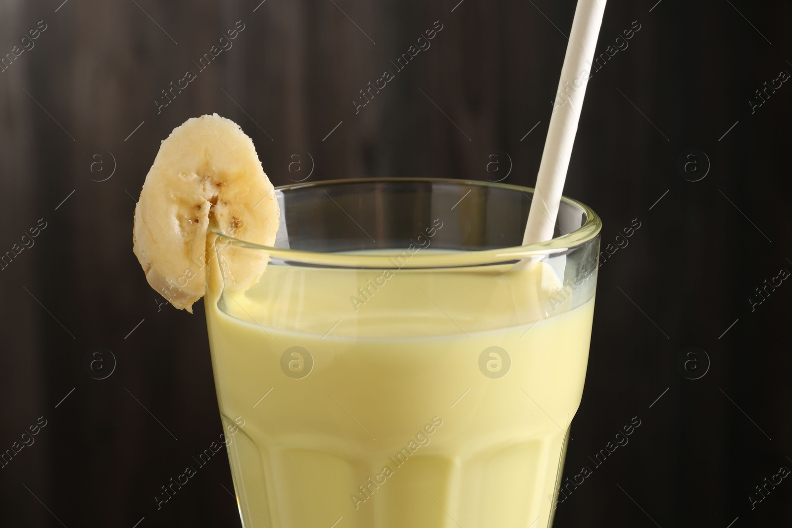Photo of Tasty banana milkshake in glass on blurred background, closeup