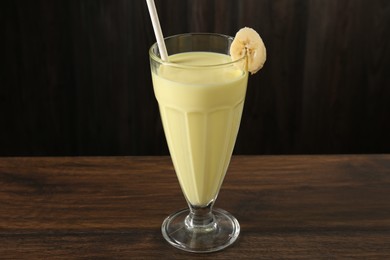 Photo of Tasty banana milkshake in glass on wooden table, closeup