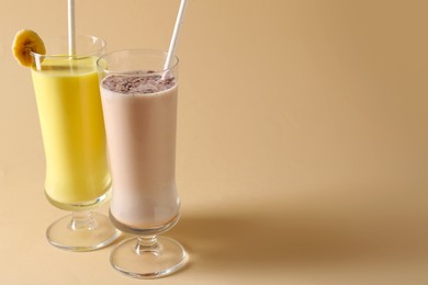Photo of Different tasty milkshakes in glasses on beige background, space for text