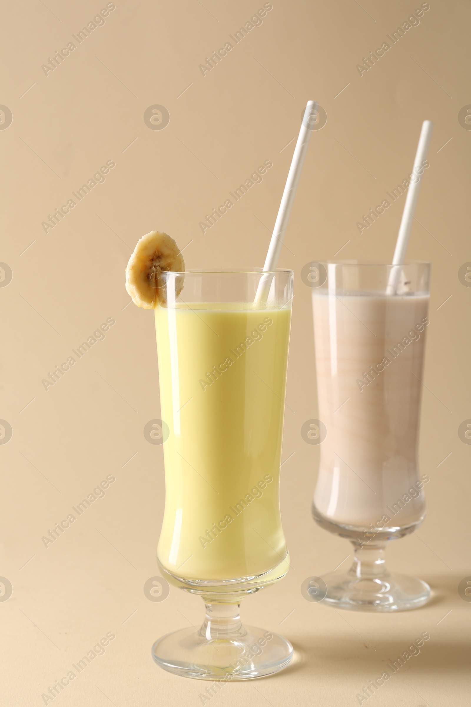 Photo of Different tasty milkshakes in glasses on beige background