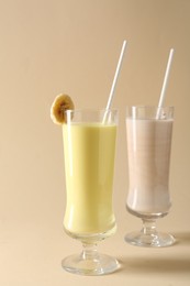 Photo of Different tasty milkshakes in glasses on beige background