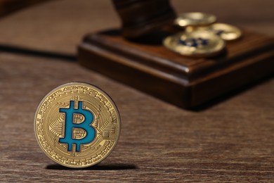 Photo of Cryptocurrency. Bitcoins and judge's gavel on wooden table, closeup
