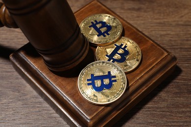 Photo of Cryptocurrency. Bitcoins and judge's gavel on wooden table, closeup