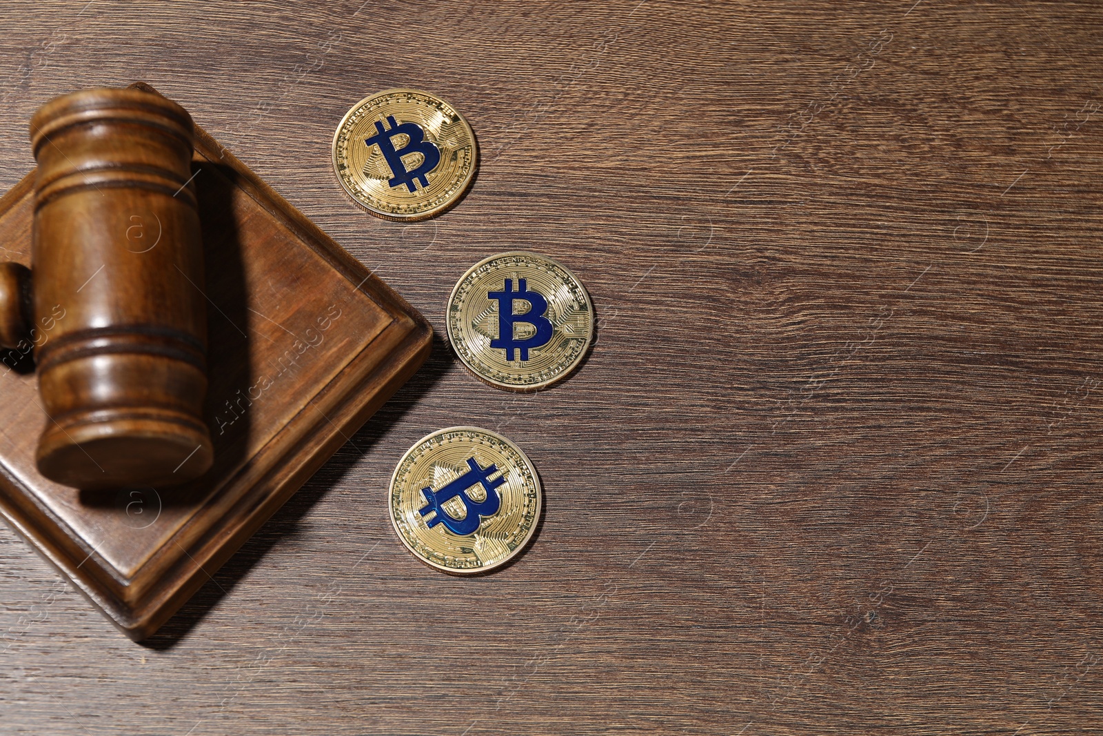 Photo of Cryptocurrency. Bitcoins and judge's gavel on wooden table, flat lay. Space for text