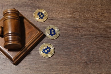 Photo of Cryptocurrency. Bitcoins and judge's gavel on wooden table, flat lay. Space for text