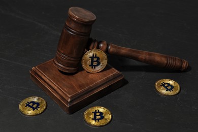 Photo of Cryptocurrency. Bitcoins and judge's gavel on black table, closeup