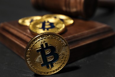 Photo of Cryptocurrency. Bitcoins and judge's gavel on black table, closeup
