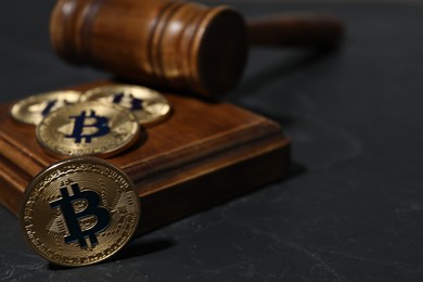 Photo of Cryptocurrency. Bitcoins and judge's gavel on black table, closeup. Space for text