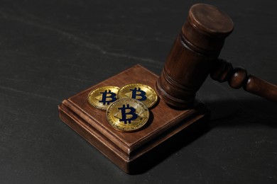 Photo of Cryptocurrency. Bitcoins and judge's gavel on black table, closeup