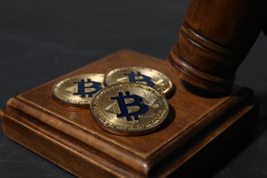 Photo of Cryptocurrency. Bitcoins and judge's gavel on black table, closeup