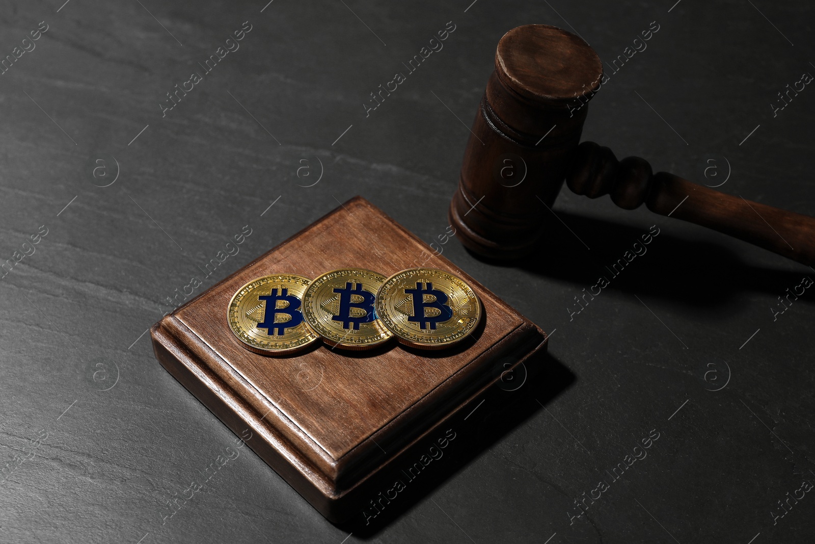 Cryptocurrency. Bitcoins and judge's gavel on black table, closeup Photo of Cryptocurrency. Bitcoins and judge's gavel on black table, closeup