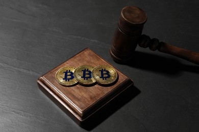 Photo of Cryptocurrency. Bitcoins and judge's gavel on black table, closeup